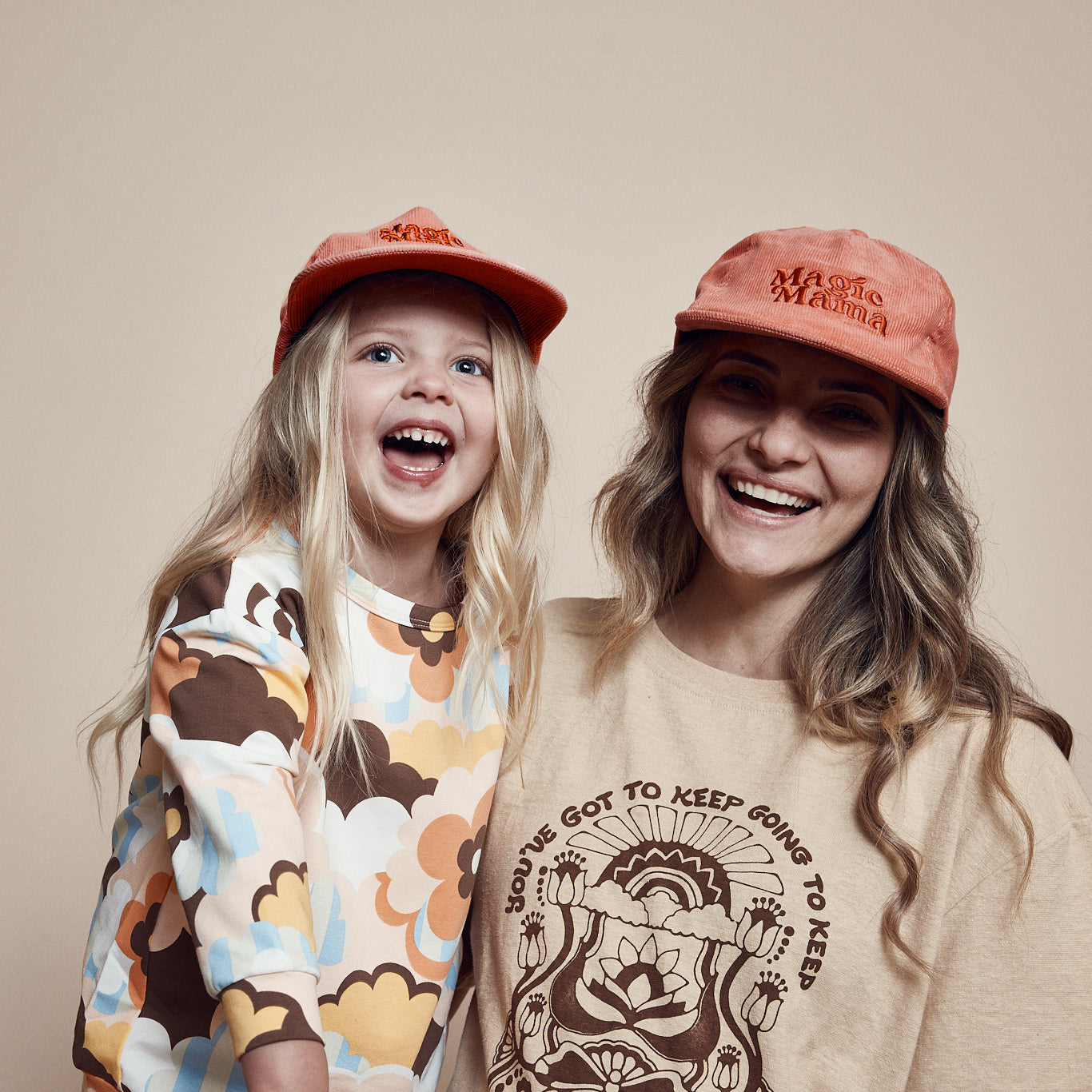 Mother and daughter wearing coordinating  Magic Mini Corduroy cap and Magic Mama corduroy cap. Both are pink with embroidery on center front in darker tone of pink.