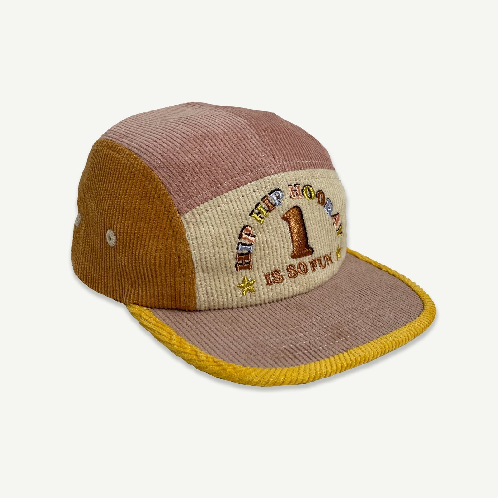 Side view of 1st Birthday Cord Cap Musk Splice. which is a 5 panel  cap , colour blocked in musk pink, orange and yellow.  Cap peak is musk pink with yellow bind. Front section is natural with embroidery in multicolored thread saying HIP HIP HOORAY, 1 IS 