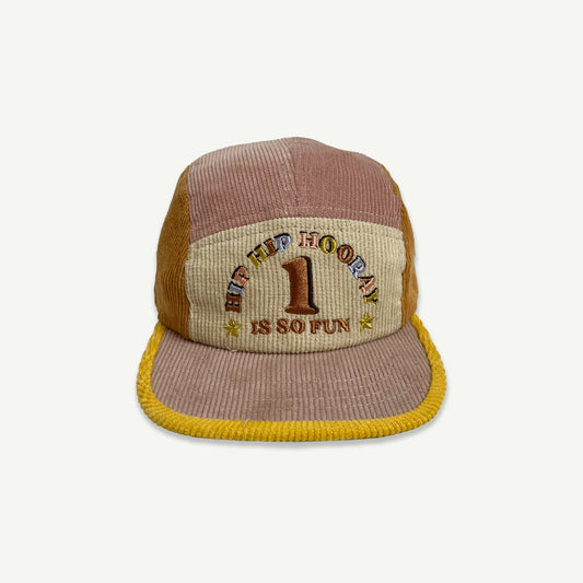 Kids 5 panel  cap ,colour blocked in musk pink, orange and yellow.  Cap peak is musk pink with yellow bind. Front section is natural with embroidery in multicolored thread saying HIP HIP HOORAY, 1 IS SO FUN. 