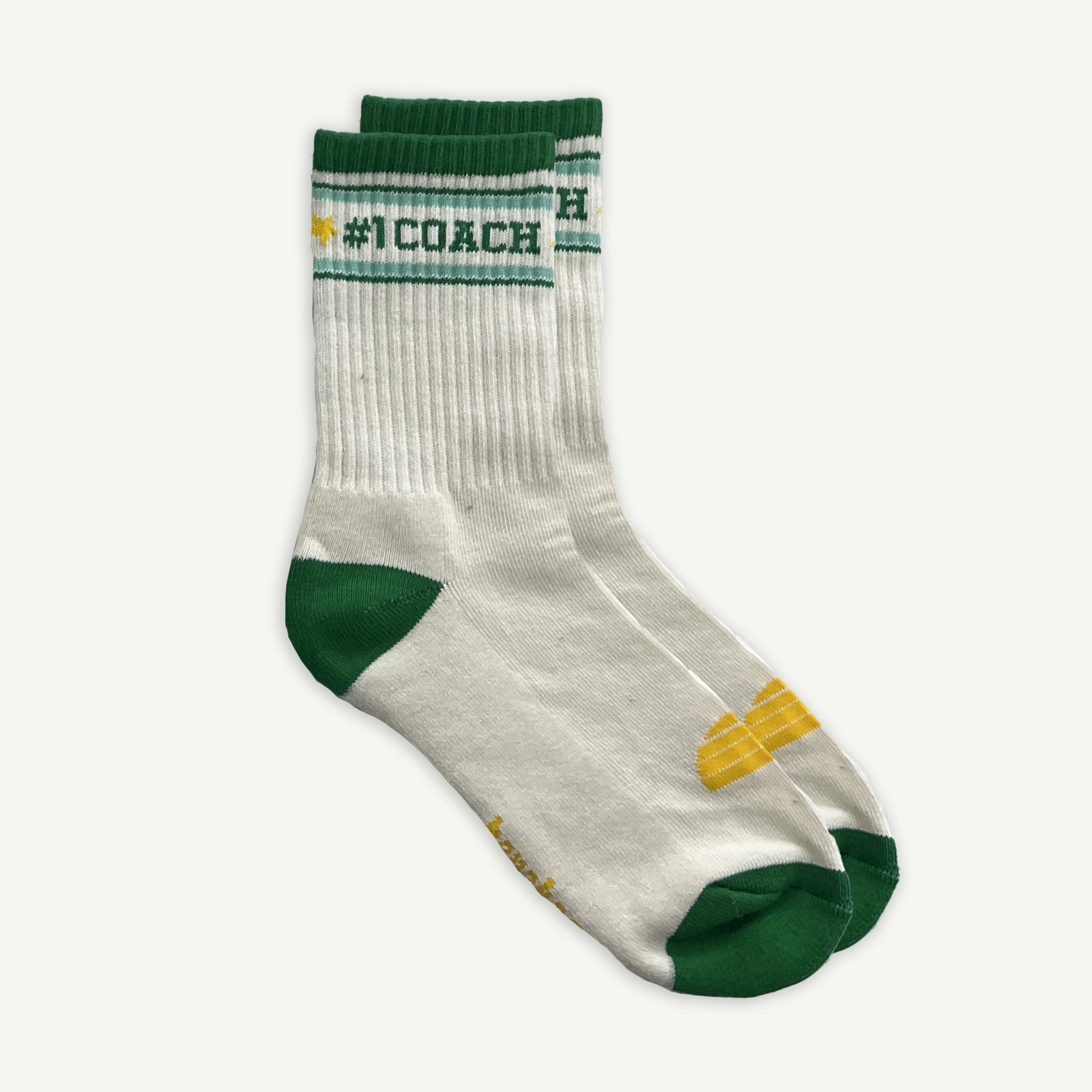 One pair of White crew socks with #1 coach in Green written horizontally, bordered with a green and aqua stripe. Toe and heal pads in contrast green with Banabae written along the sole in yellow, and the iconic  Banabae sun logo in yellow placed on top of